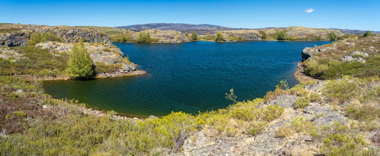 Laguna de aguas azules entre roquedos y matorral