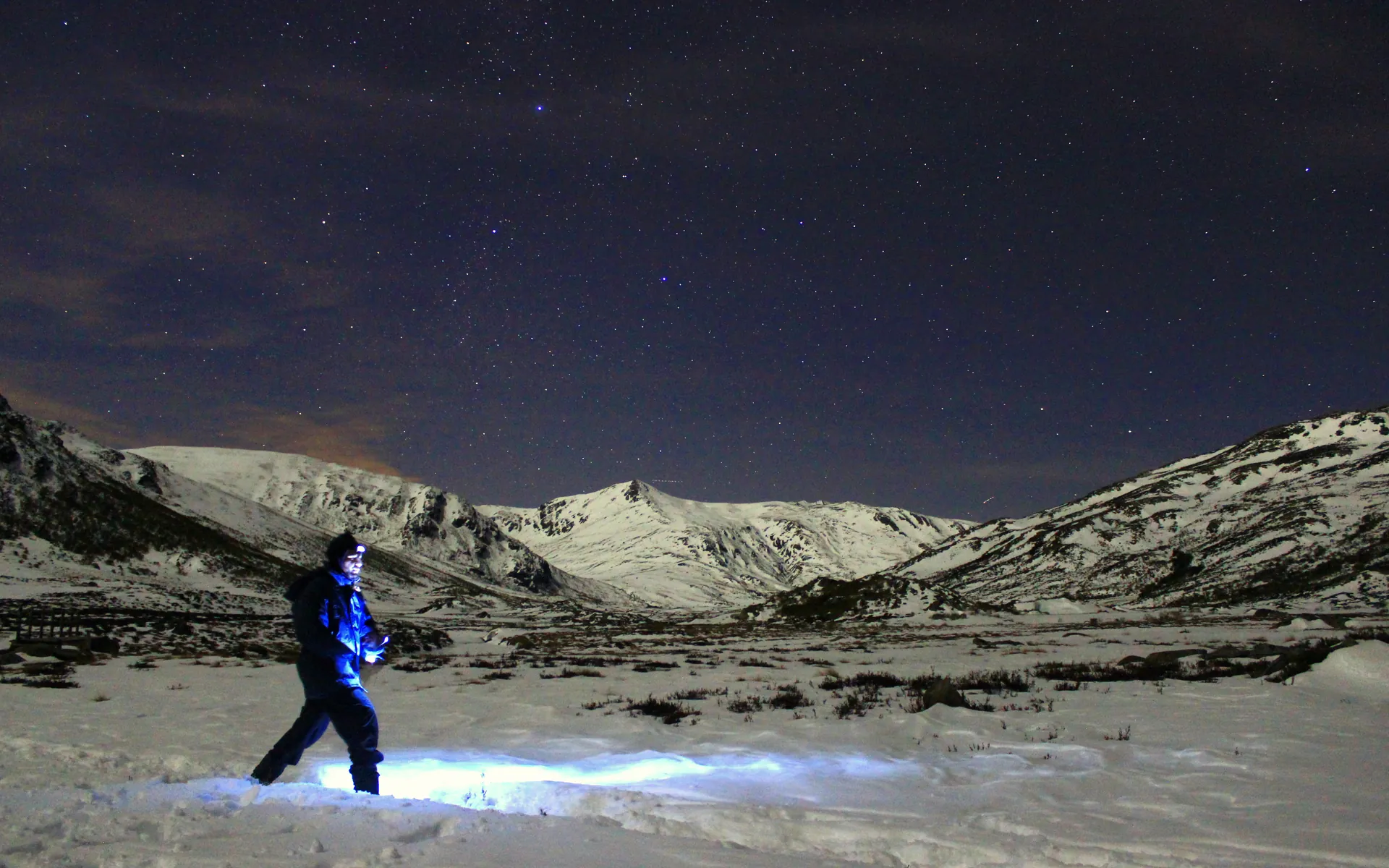 Montañero con frontal bajo un cielo estrellado sobre las cumbres nevadas de la Alta Sanabria